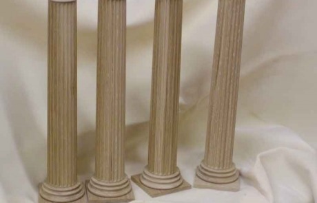 Four white oak wood columns standing in a row against a white draped background.