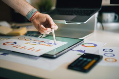 A hand pointing to a budget graph to calculate savings from purchasing in bulk.